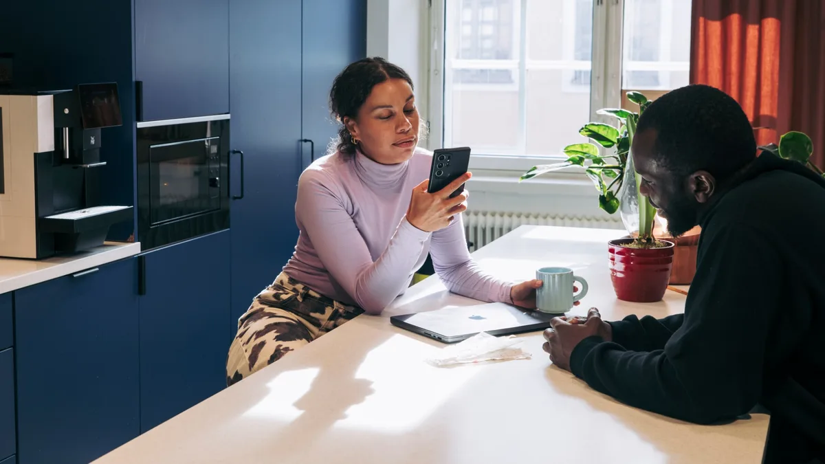 A small business owner photographing a paper receipt with SparkReceipt on her phone at the office kitchen table